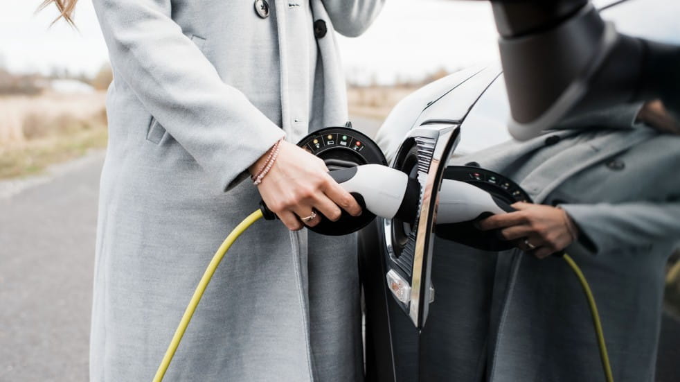 woman in winter coat charging ev